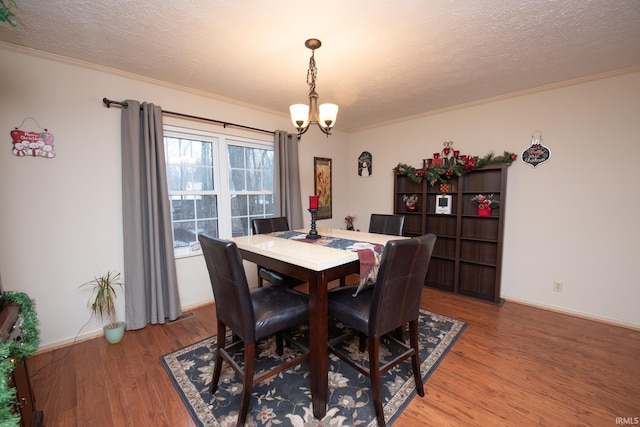 dining area featuring hardwood / wood-style flooring, a notable chandelier, crown molding, and a textured ceiling