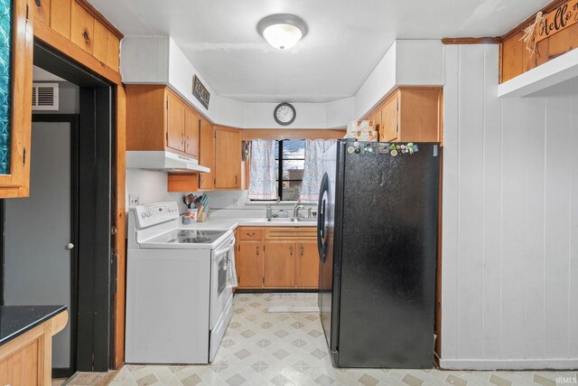 kitchen featuring black refrigerator, electric range, and wood walls