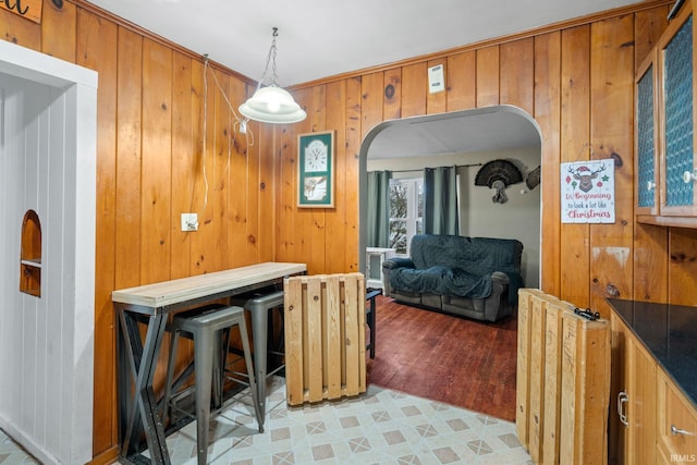 dining room with wood walls, light wood-type flooring, and crown molding