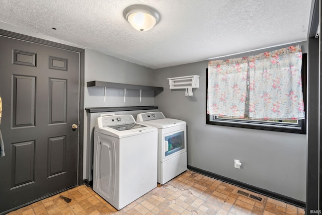 washroom with washer and clothes dryer and a textured ceiling