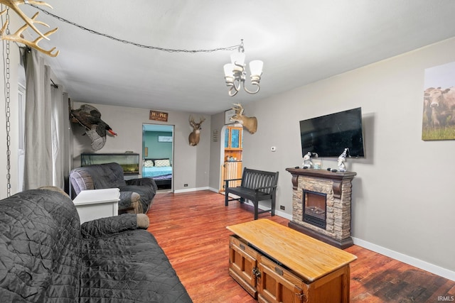 living room with a stone fireplace, hardwood / wood-style floors, and a chandelier