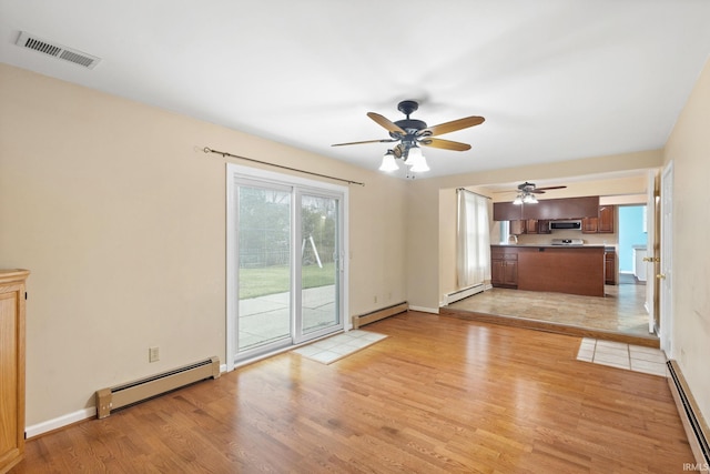 unfurnished living room featuring baseboard heating and light hardwood / wood-style floors