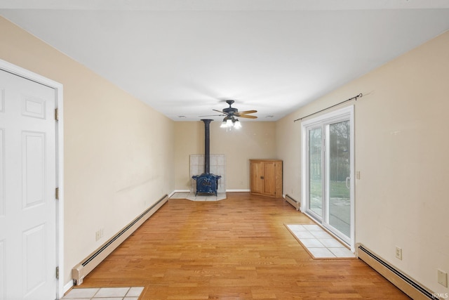 unfurnished living room with a wood stove, light hardwood / wood-style flooring, and a baseboard radiator