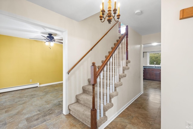 staircase featuring baseboard heating, sink, and ceiling fan with notable chandelier