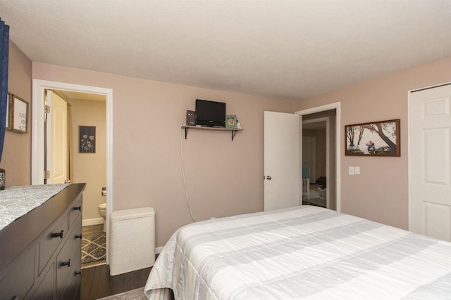 bedroom featuring dark hardwood / wood-style floors, a textured ceiling, and connected bathroom