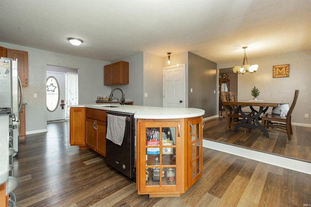 kitchen with appliances with stainless steel finishes, a kitchen island with sink, dark wood-type flooring, sink, and a notable chandelier