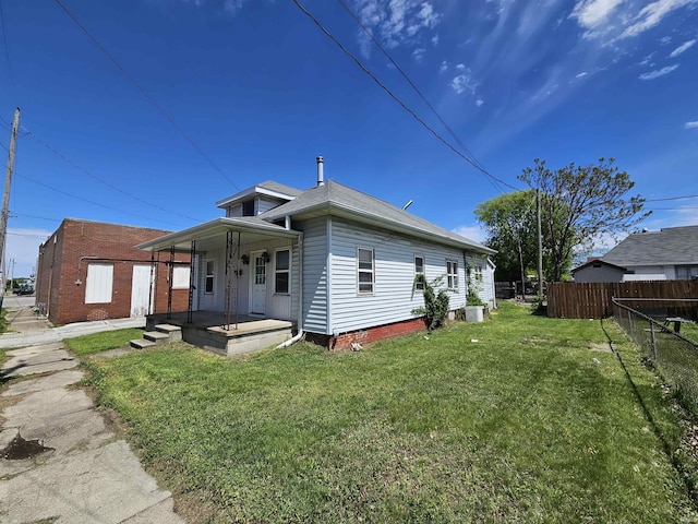 back of property featuring covered porch and a lawn