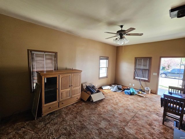 misc room featuring dark colored carpet, ceiling fan, and a wealth of natural light