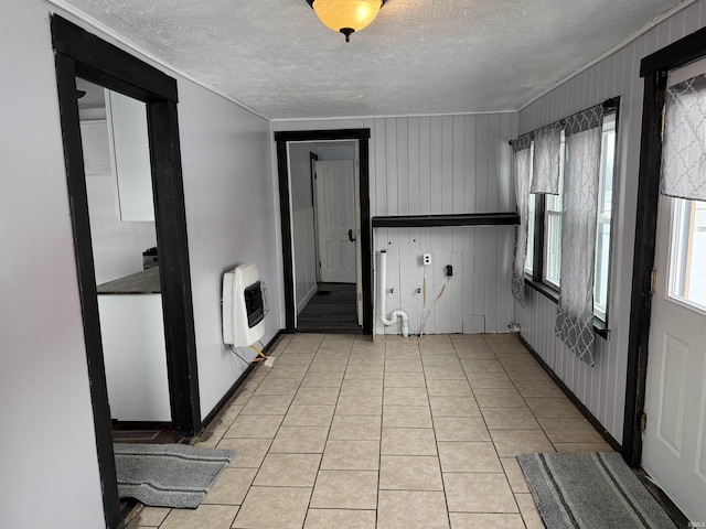 kitchen with light tile patterned floors, a textured ceiling, heating unit, and wooden walls