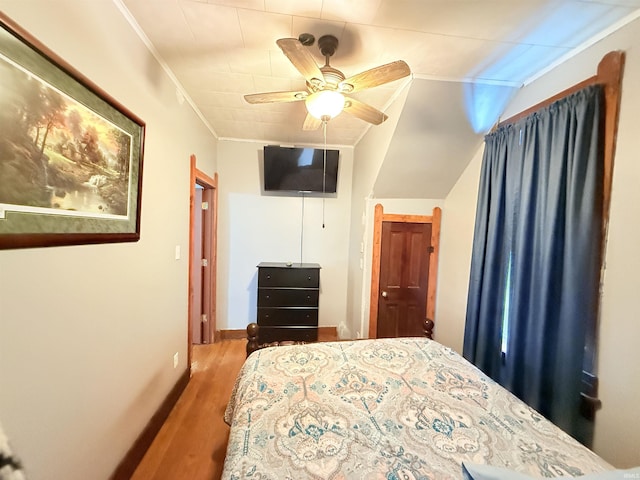 bedroom with wood-type flooring, vaulted ceiling, ceiling fan, and ornamental molding