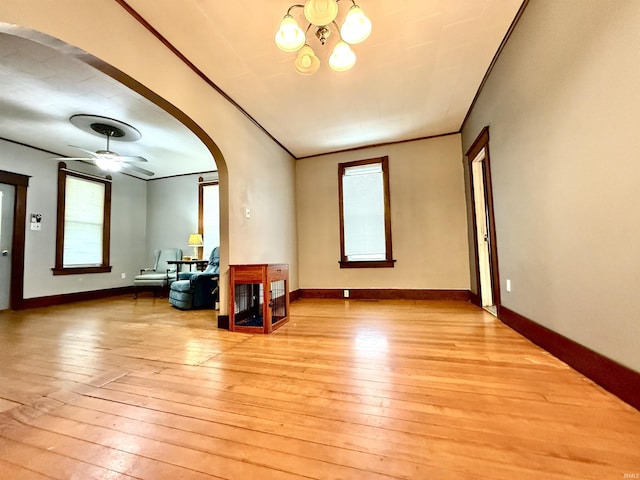 living room featuring light hardwood / wood-style floors, ceiling fan with notable chandelier, and ornamental molding