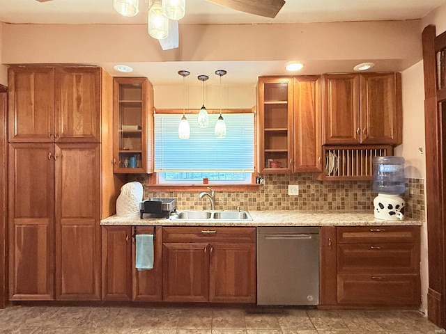 kitchen featuring tasteful backsplash, light stone counters, sink, dishwasher, and hanging light fixtures