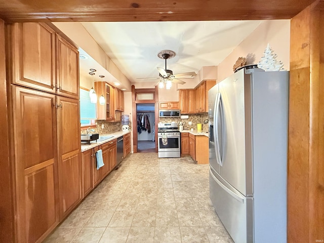 kitchen with decorative backsplash, ceiling fan, stainless steel appliances, and decorative light fixtures