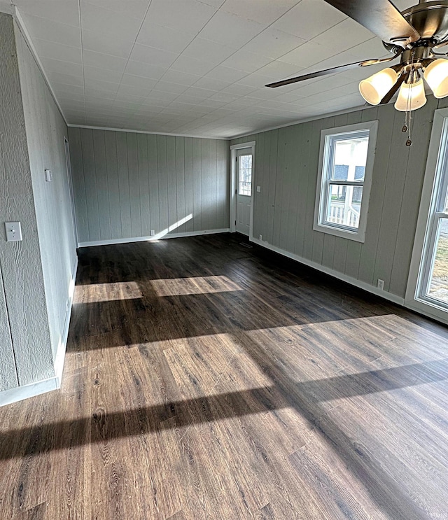 spare room with ceiling fan, dark wood-type flooring, and wood walls