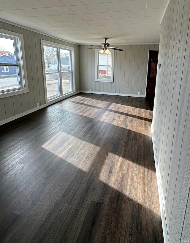 unfurnished room featuring dark hardwood / wood-style flooring, a wealth of natural light, and wooden walls