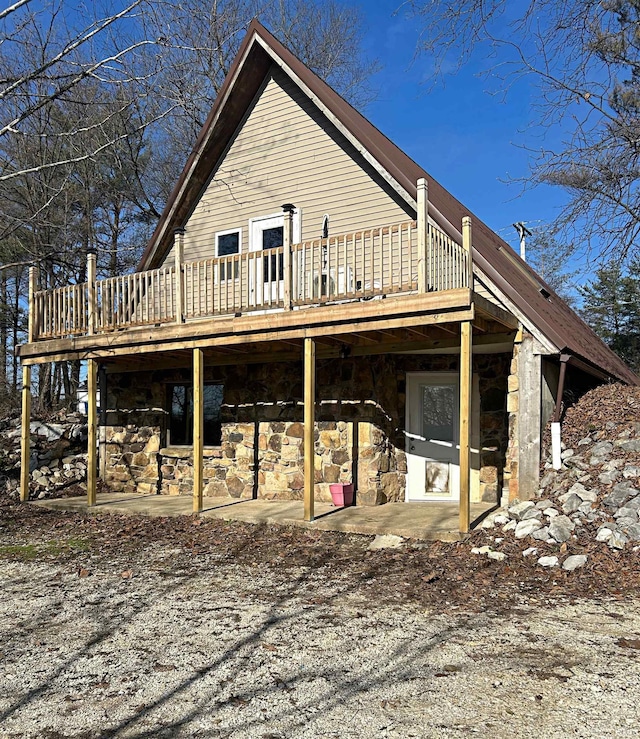 back of house featuring a wooden deck and a patio