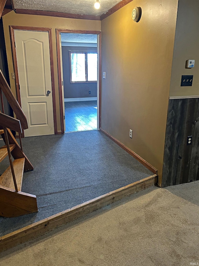 corridor featuring carpet flooring, a textured ceiling, and ornamental molding