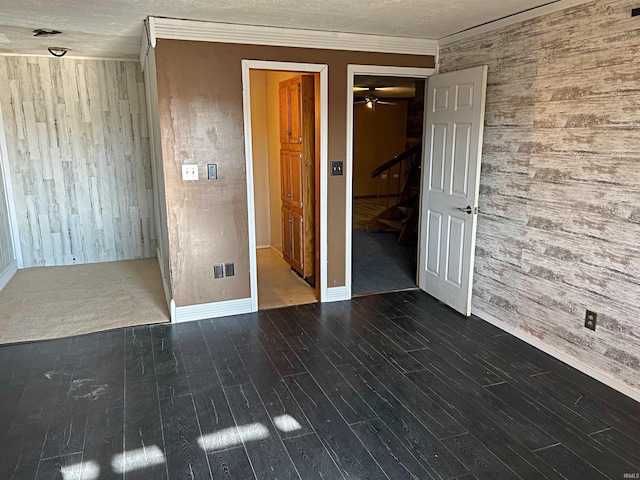 unfurnished room with a textured ceiling, dark hardwood / wood-style floors, ceiling fan, and ornamental molding