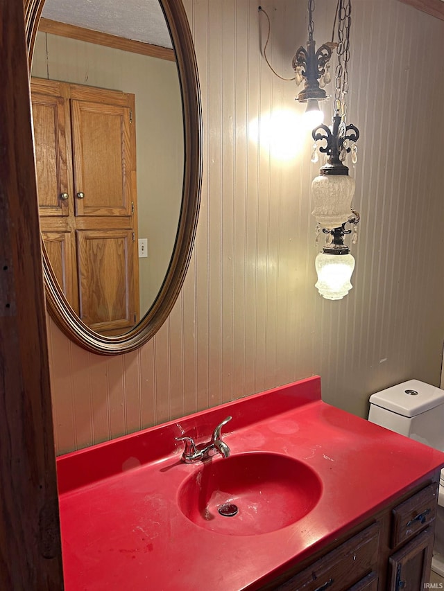 bathroom with vanity, toilet, ornamental molding, and wooden walls