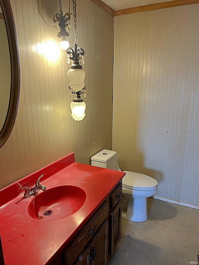 bathroom with vanity, wooden walls, toilet, and ornamental molding