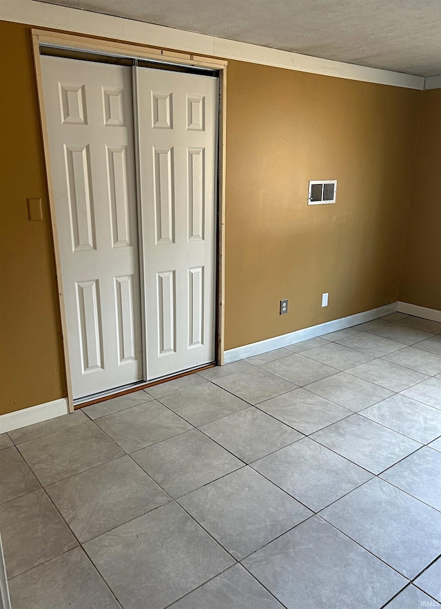 unfurnished bedroom with light tile patterned floors, a textured ceiling, and a closet