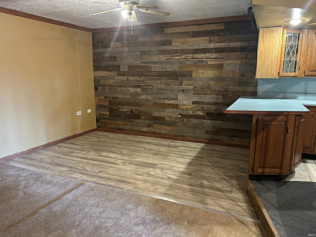 interior space featuring wood walls, crown molding, ceiling fan, a textured ceiling, and light hardwood / wood-style floors