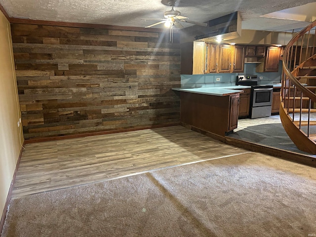 kitchen with a textured ceiling, electric range, light hardwood / wood-style flooring, and wooden walls