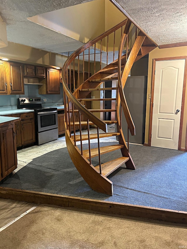 staircase with carpet floors and a textured ceiling