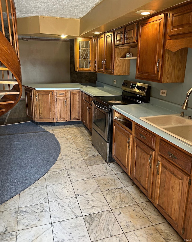 kitchen with a textured ceiling, stainless steel range with electric cooktop, and sink