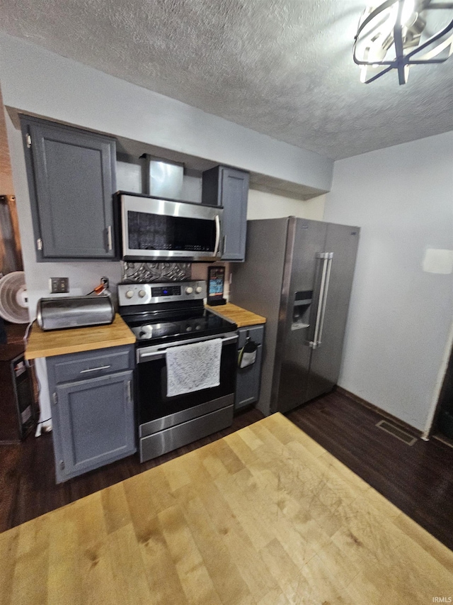 kitchen with wooden counters, stainless steel appliances, and dark hardwood / wood-style floors