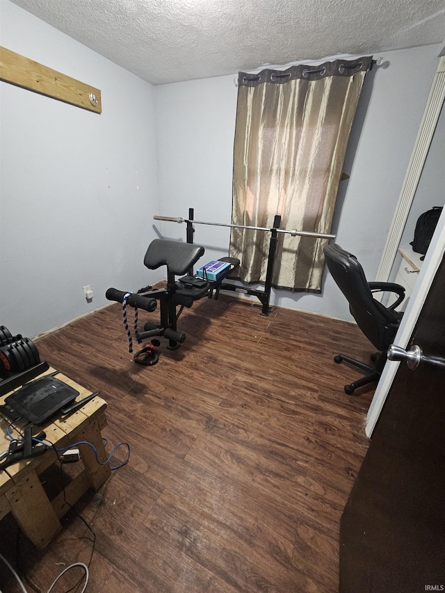 workout room with dark wood-type flooring and a textured ceiling