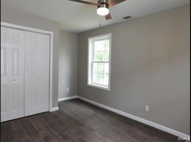 unfurnished bedroom featuring dark wood-type flooring, ceiling fan, and a closet