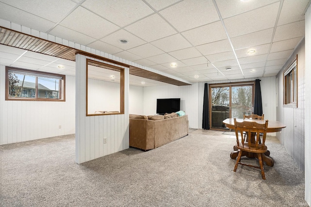 carpeted living room featuring a paneled ceiling and wooden walls