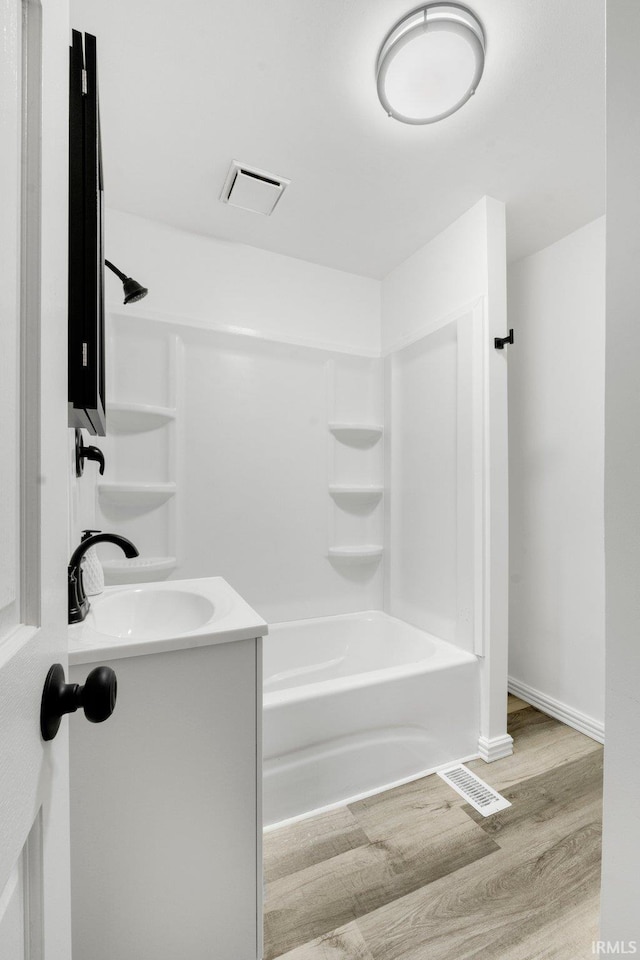 bathroom featuring vanity, washtub / shower combination, and hardwood / wood-style flooring