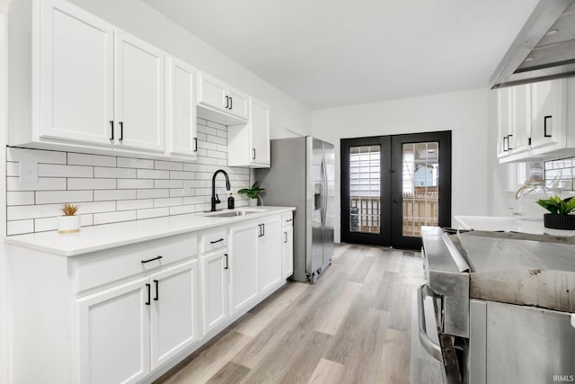 kitchen featuring decorative backsplash, french doors, sink, light hardwood / wood-style floors, and white cabinetry