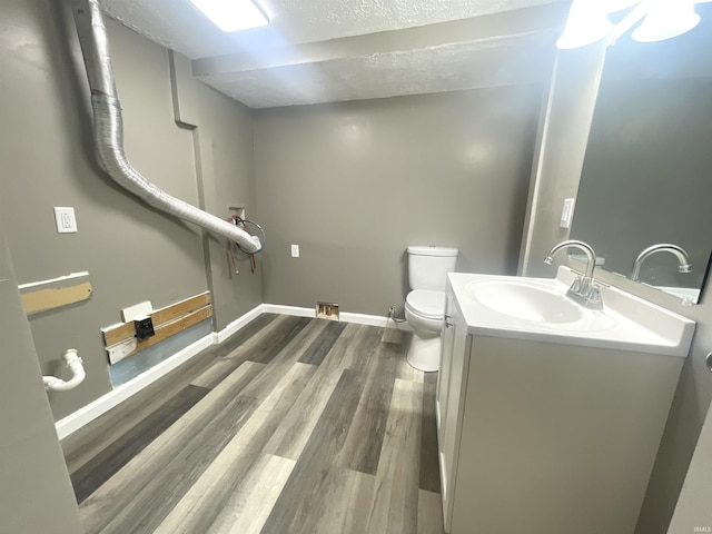 bathroom with hardwood / wood-style floors, vanity, toilet, and a textured ceiling