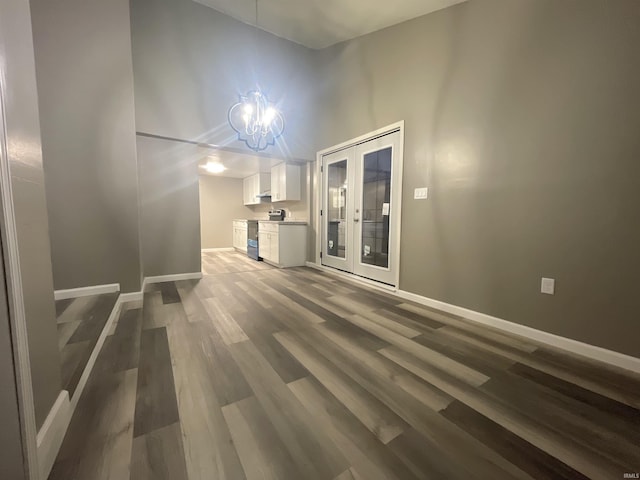 spare room featuring french doors, a notable chandelier, and wood-type flooring