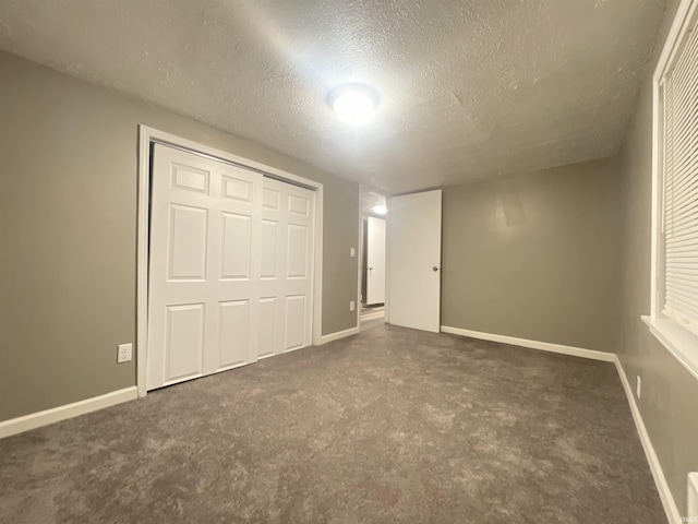 unfurnished bedroom featuring dark carpet, a textured ceiling, and a closet