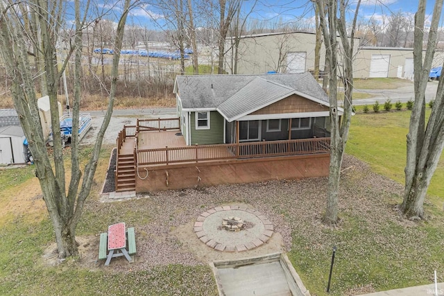 view of front of house featuring a wooden deck, a sunroom, a front lawn, and a fire pit