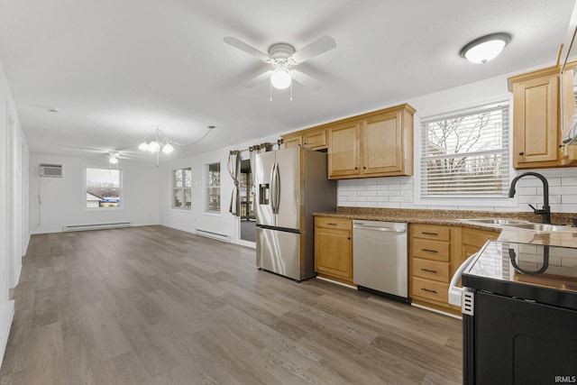 kitchen featuring wood-type flooring, baseboard heating, stainless steel appliances, and tasteful backsplash