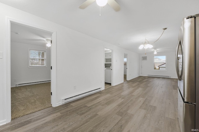 interior space featuring ceiling fan with notable chandelier, light hardwood / wood-style floors, and a baseboard heating unit