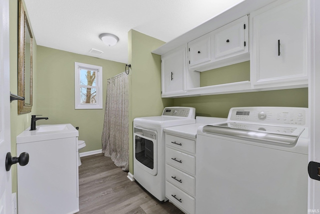 clothes washing area featuring light wood-type flooring, independent washer and dryer, and sink