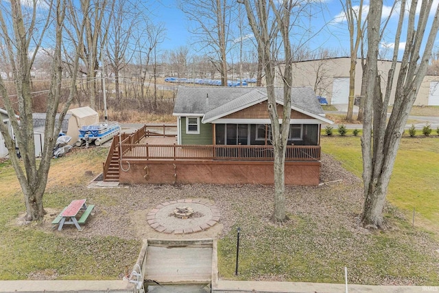 view of front of house with a front lawn, an outdoor fire pit, a wooden deck, and a sunroom