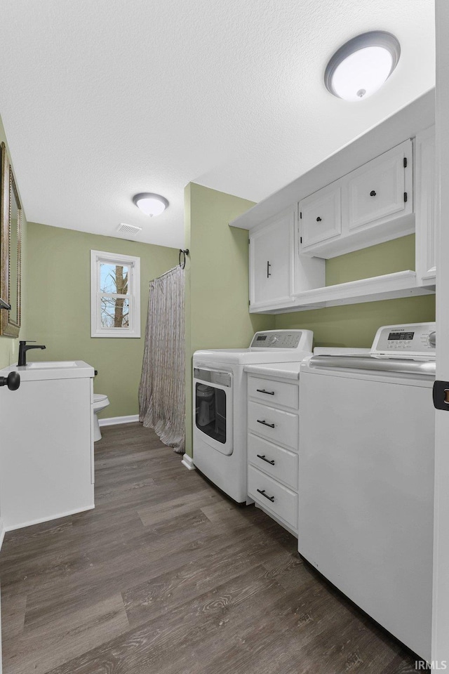 laundry area with washing machine and clothes dryer, dark wood-type flooring, and a textured ceiling