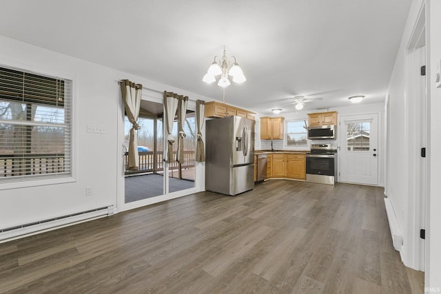 kitchen with hardwood / wood-style flooring, a healthy amount of sunlight, baseboard heating, and appliances with stainless steel finishes