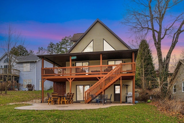 back house at dusk with a wooden deck, a patio area, and a yard