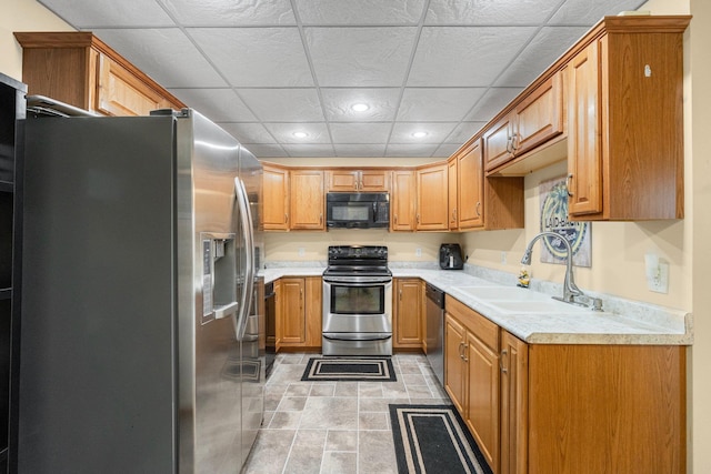 kitchen with a paneled ceiling, sink, light tile patterned floors, and stainless steel appliances