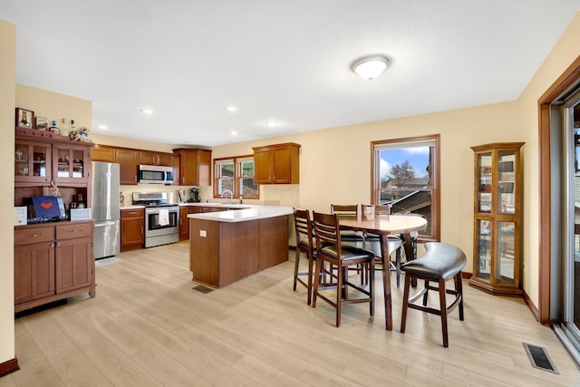 kitchen featuring sink, a kitchen island, stainless steel appliances, and light wood-type flooring