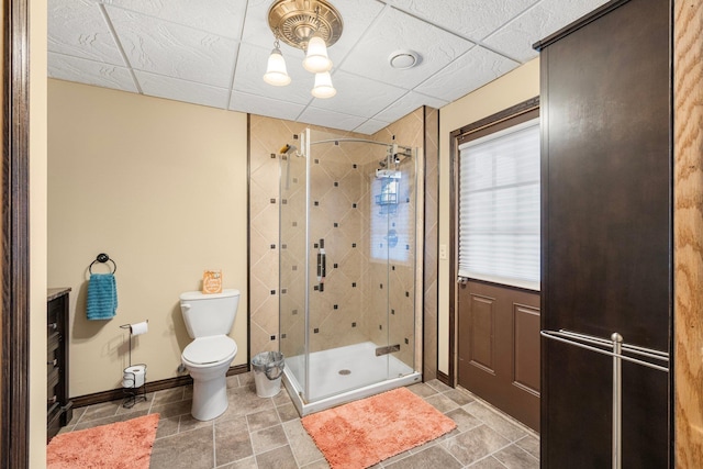 bathroom with a drop ceiling, toilet, and walk in shower