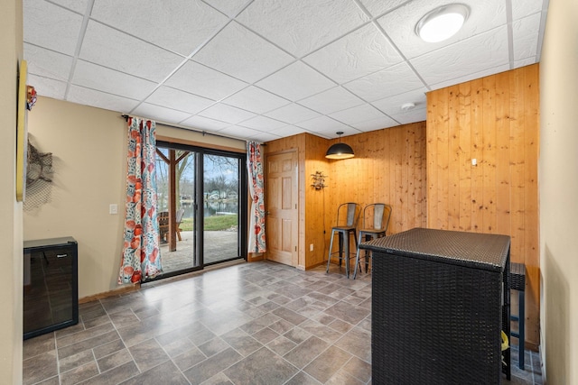 interior space featuring a drop ceiling and wood walls